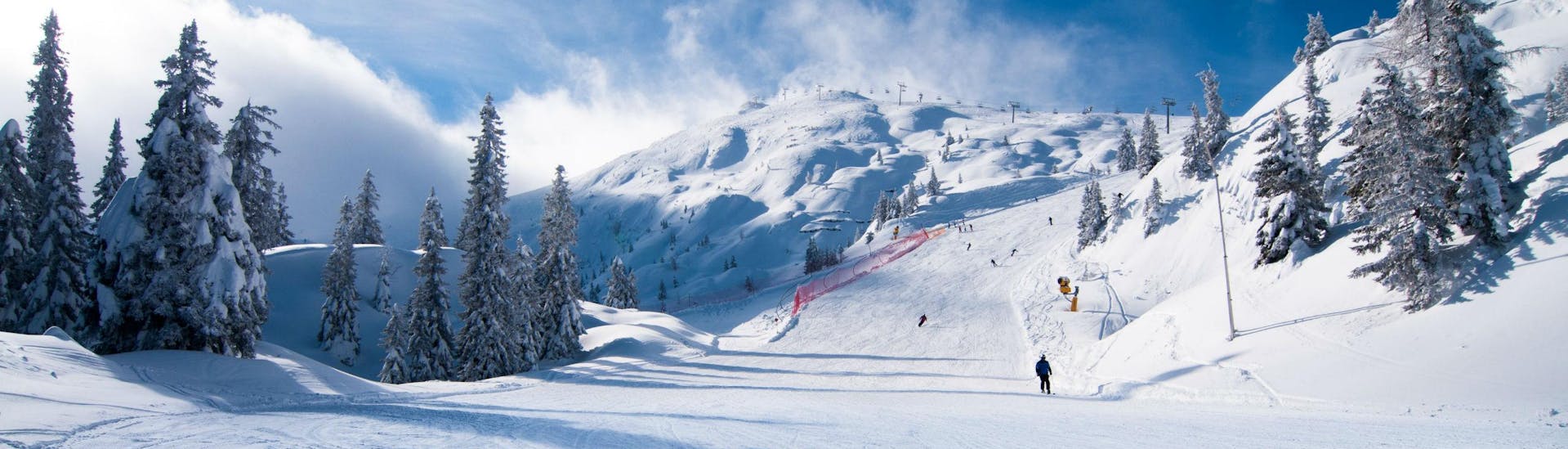 A couple of skiers can be seen skiing down a freshly groomed ski slope in the Italian ski resort of Andalo, where local ski schools offer a variety of ski lessons.