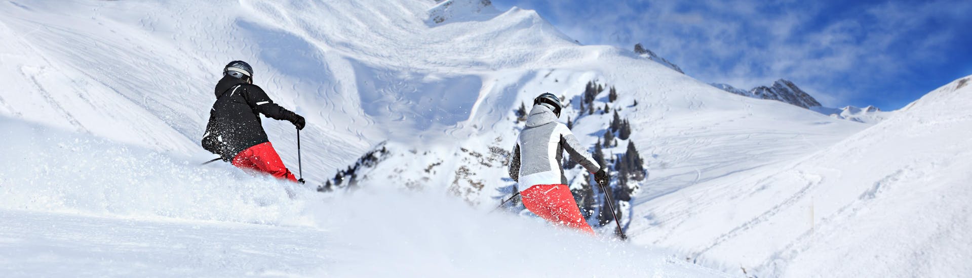 Una vista panoramica del paesaggio montano mentre le persone imparano a siare grazie alle lezioni di sci di una scuola di sci locale presso Ski Arlberg.