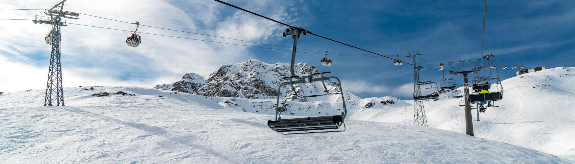 Ein Bild eines Sessellifts und einer Gondel im schweizerischen Skigebiet Arosa, wo örtliche Skischulen ihre Skikurse für Besucher, die das Skifahren lernen wollen, anbieten.