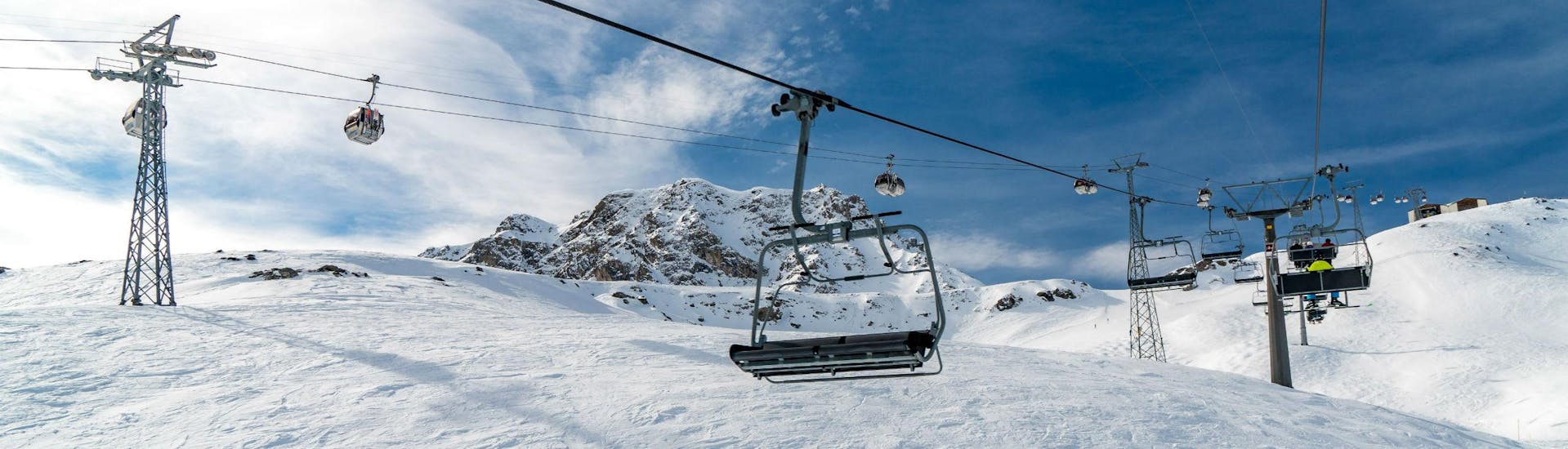 Ein Bild eines Sessellifts und einer Gondel im schweizerischen Skigebiet Arosa, wo örtliche Skischulen ihre Skikurse für Besucher, die das Skifahren lernen wollen, anbieten.