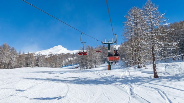 Veduta di uno skilift che trasporta gli sciatori fino in cima alla montagna nel comprensorio sciistico di Bardonecchia, dove le scuole di sci locali offrono un'ampia scelta di lezioni di sci.