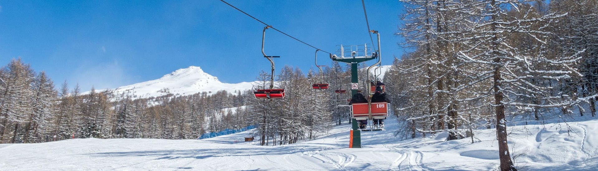 View of a ski lift transporting skiers up to the top of the mountain in the ski resort of Bardonecchia, where local ski schools offer a broad selection of ski lessons.