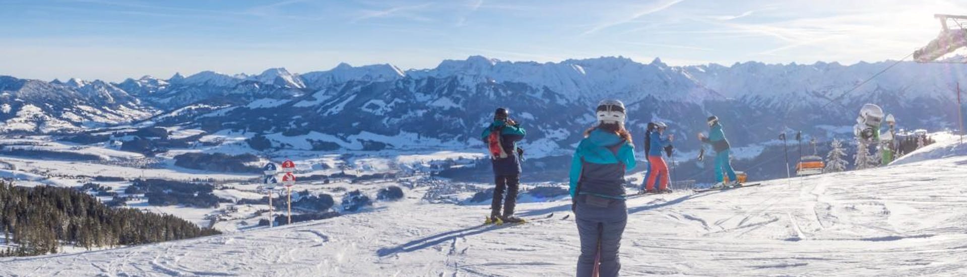 Eine Gruppe Skifahrer steht an der Spitze des Bergs und blickt über das bayrische Skigebiet Bolsterlang, wo örtliche Skischulen Skikurse für diejenigen anbieten, die das Skifahren lernen möchten.