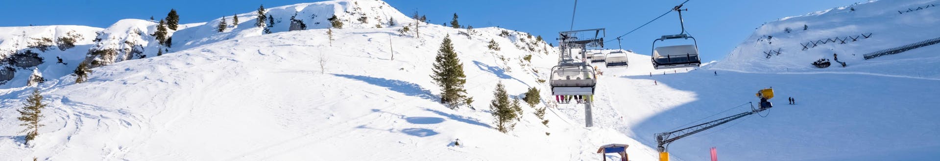 Día soleado en las pistas con gente esquiando y subiendo las colinas con el remonte.