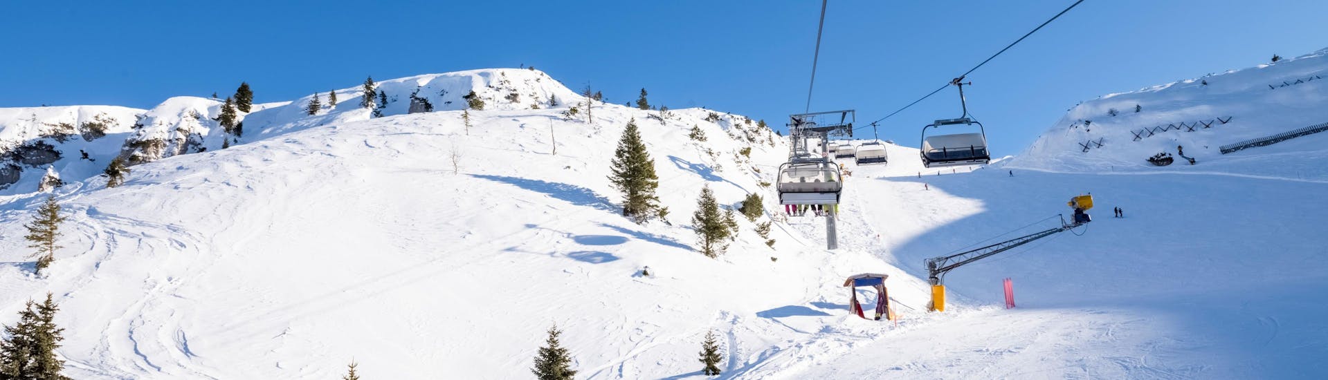 Zonnige dag op de pistes met mensen die naar beneden skiën en met de skilift naar boven gaan.