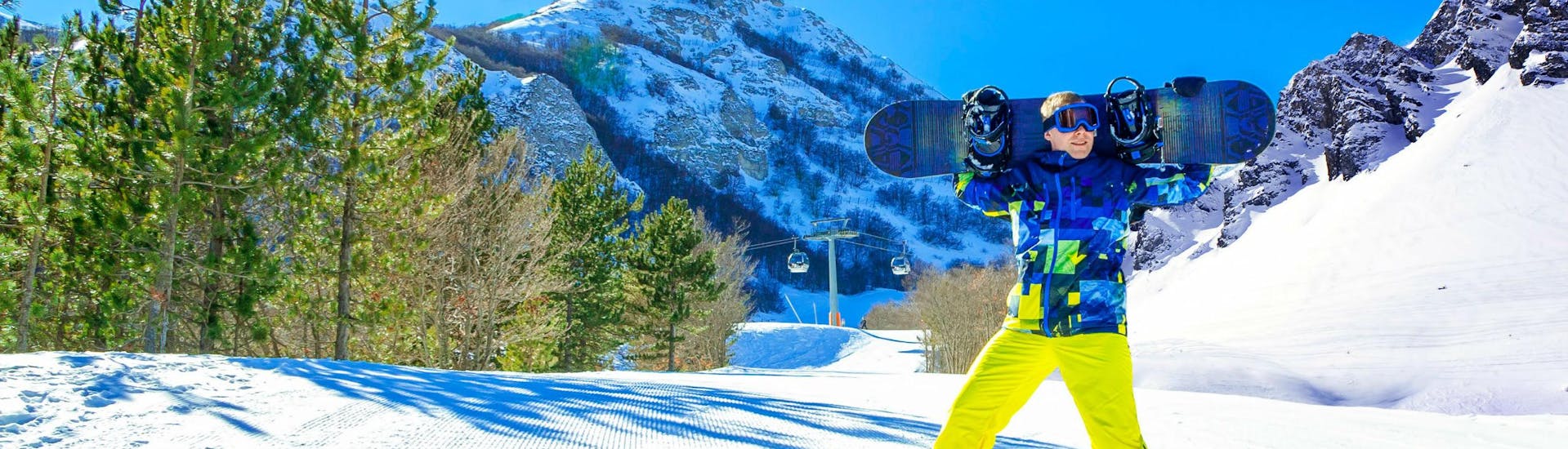 Uno snowboarder sta sorridendo alla fotocamera su una pista soleggiata del comprensorio sciistico di Campo Felice, dove è possibile scegliere tra un'ampia gamma di corsi di sci e snowboard offerti dalle scuole di sci locali.