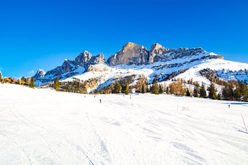 Des skieurs sur les pistes de Carezzo al Lago par une journée d'hiver ensoleillée.