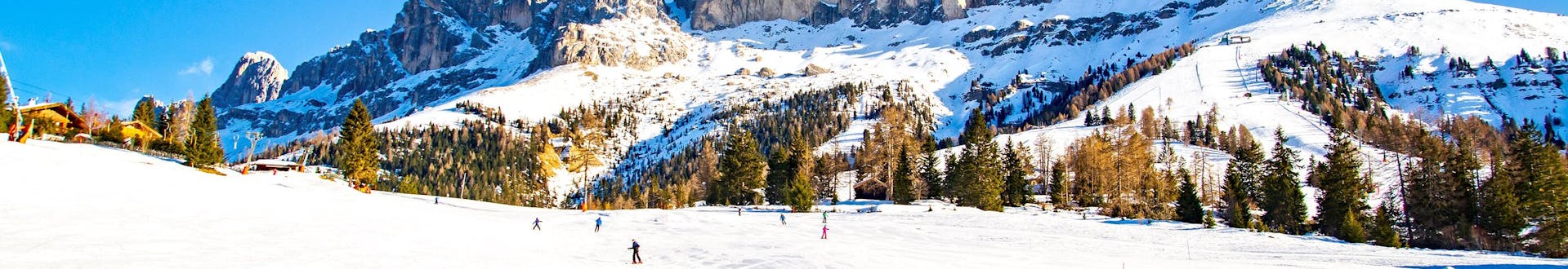 Des skieurs sur les pistes de Carezzo al Lago par une journée d'hiver ensoleillée.