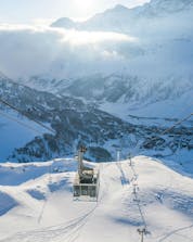 Una funivia sta risalendo i pendii del comprensorio sciistico di Cervinia, dove i turisti possono imparare a sciare grazie alle lezioni di sci impartite dalle scuole di sci locai.