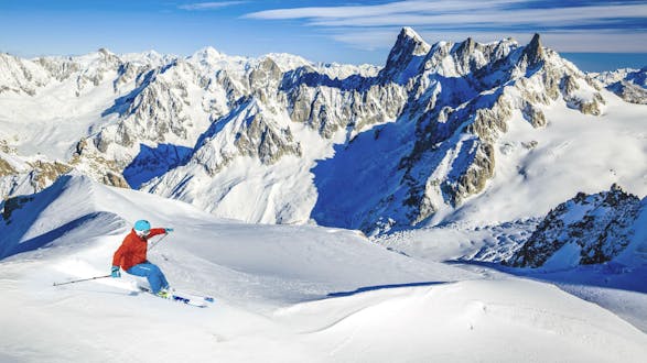 A skier is skiing through fresh powder snow on one of the slopes in Chamonix - Mont Blanc, where local ski schools offer a variety of ski lessons.