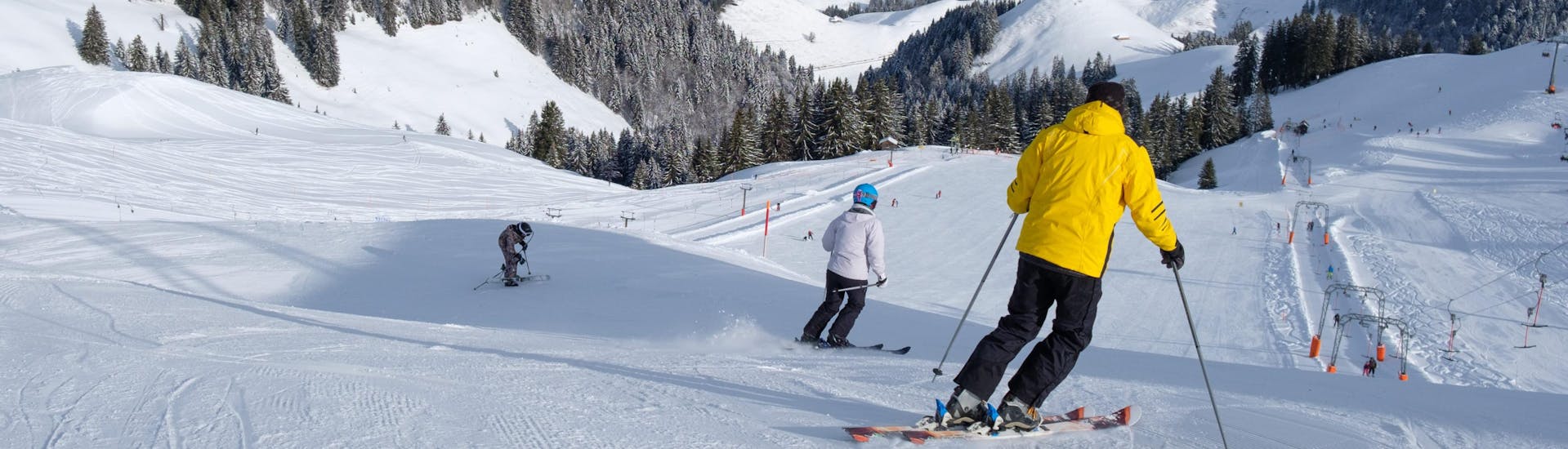 Mehrere Skifahrer fahren auf einer frisch präparierten Piste im schweizerischen Skigebiet Charmey, einem beliebten Ort für angehende Skifahrer die bei einer örtlichen Skischule einen Skikurs buchen wollen.