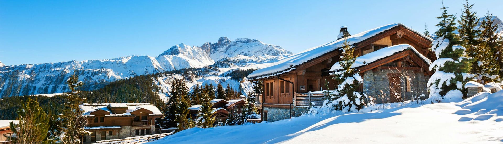An image of a couple of snow-covered mountain huts in the popular French ski resort of Courchevel, where visitors can learn to ski in one of the many ski lessons organised by the local ski schools.