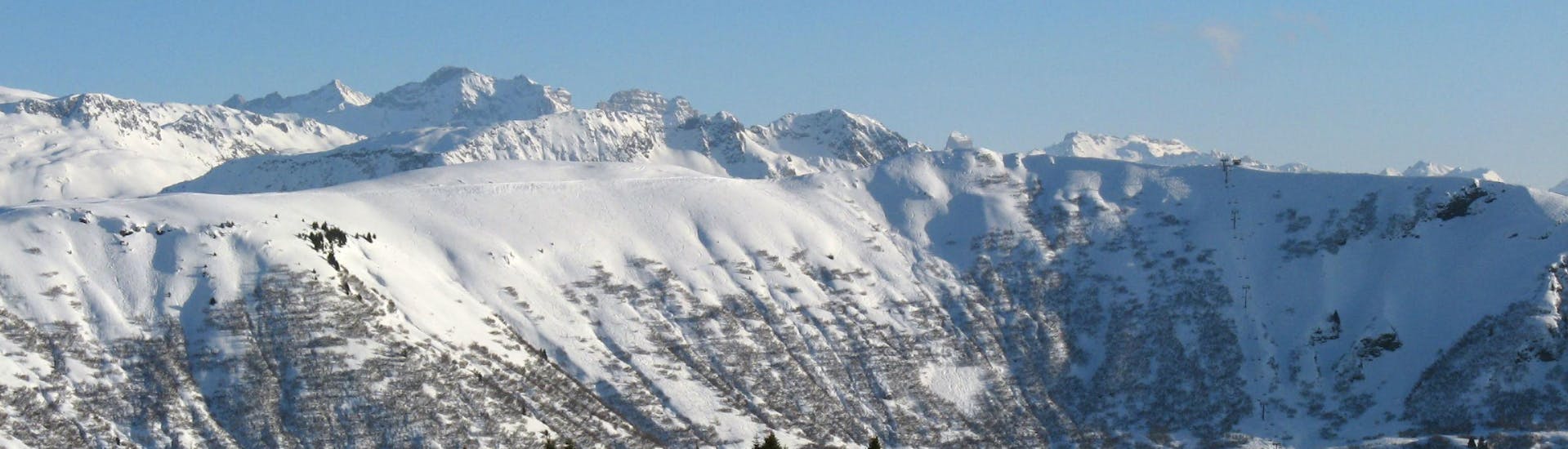 Une vue panoramique des pistes de ski de Crest-Voland Cohennoz, une station de ski française nichée entre les majestueux sommets du département de la Savoie, où les écoles de ski locales offrent un large choix de cours de ski.
