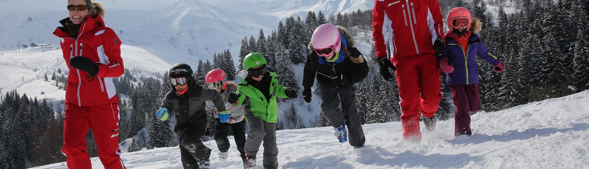 Instructors of the ESF Valmorel  and young skiers having fun on the slopes during a ski lesson. 