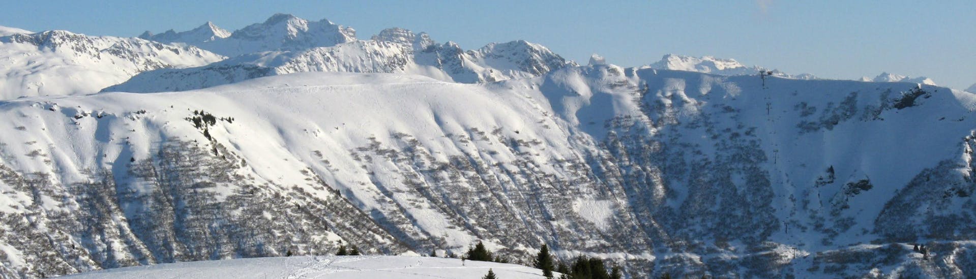 Une vue panoramique des pistes de ski de l'Espace Diamant, un domain skiable française nichée entre les majestueux sommets du département de la Savoie, où les écoles de ski locales offrent un large choix de cours de ski.