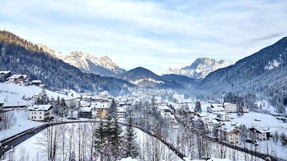 An image of Falcade, a picturesque Italian village nestled between the mountains, where aspiring skiers can book ski lessons with one of the local ski schools.