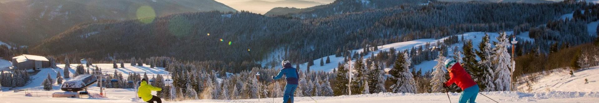 Two skiers and a snowboarder are drawing their tracks in the snow on the ski slopes of Feldberg, where local ski schools offer their ski lessons. 