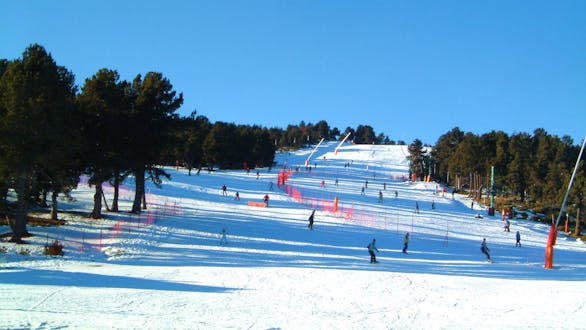 Skiers are skiing down one of the snowy slopes of the French ski resort Font Romeu in the Pyrenees.
