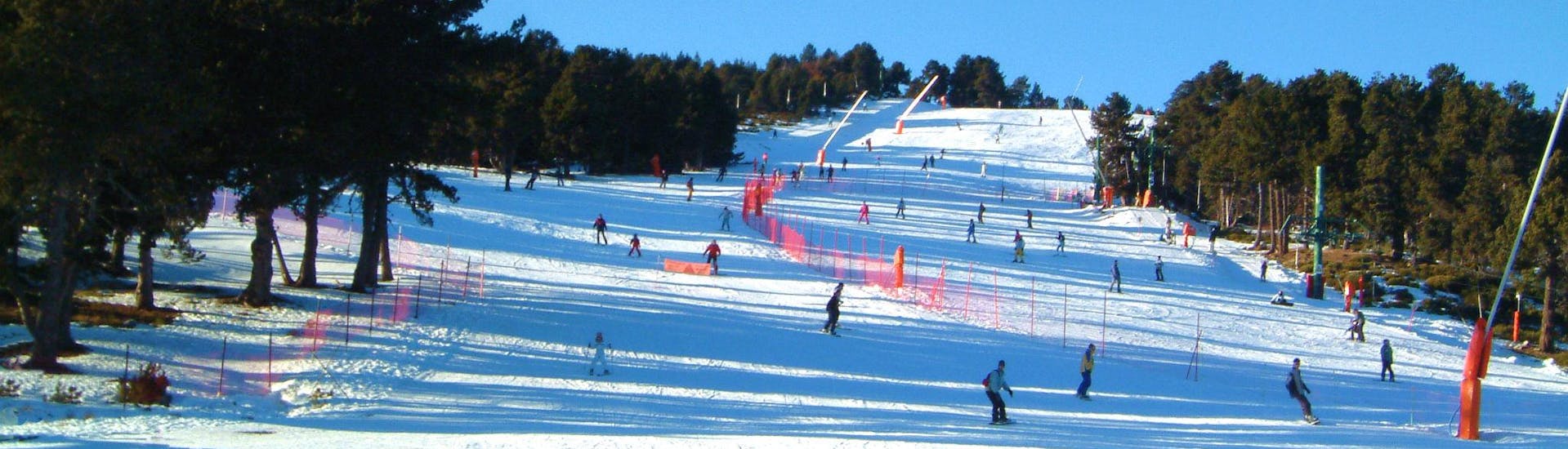 Des skieurs descendent l'une des pistes enneigée de la station de ski française de Font Romeu dans les Pyrénées.