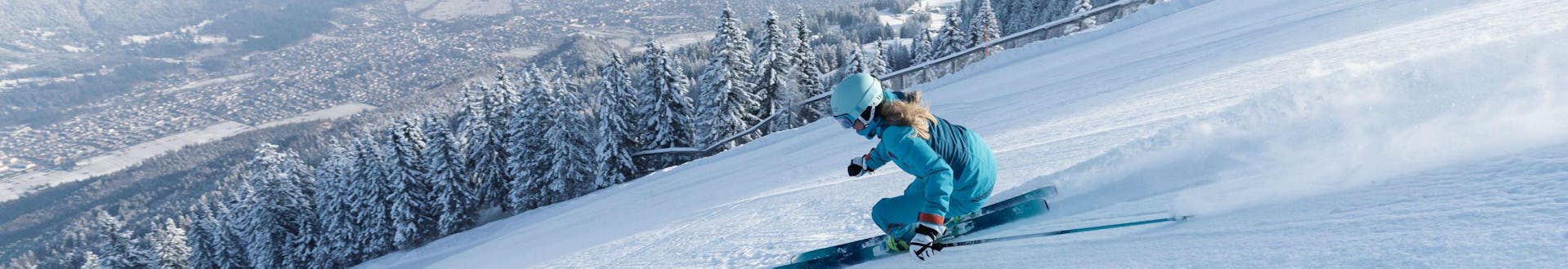 Eine Skifahrerin zieht eine perfekt präparierte Piste mit Blick auf das Skigebiet Garmisch-Classic hinunter, wo auch die örtlichen Skischulen eine Bandbreite an Skikursen anbieten. (c)Bayerische Zugspitzbahn Bergbahn AGfendstudios.com