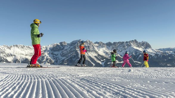 Eine Familie verbringt einen gemeinsamen Tag auf den Skipisten von Going-Ellmau, wo örtliche Skischulen ihre Skikurse für all jene die das Skifahren lernen wollen durchführen.