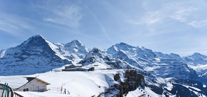 Blick auf die schneebedeckte Berglandschaft rund um die Bergstation der Gondel im schweizer Skigebiet Interlaken.