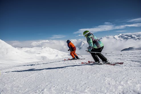 Zwei Skifahrer beim Skifahren auf einer frisch präparierten Piste in Klosters, einem beliebten schweizer Skigebiet in dem viele bei einer der örtlichen Skischulen einen Skikurs buchen.