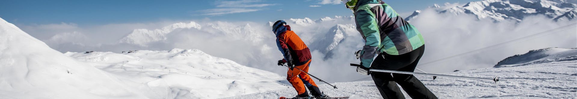Two skiers are skiing down a freshly prepared slope in the Swiss ski resort of Klosters, a popular place to book ski lessons with one of the local ski schools.