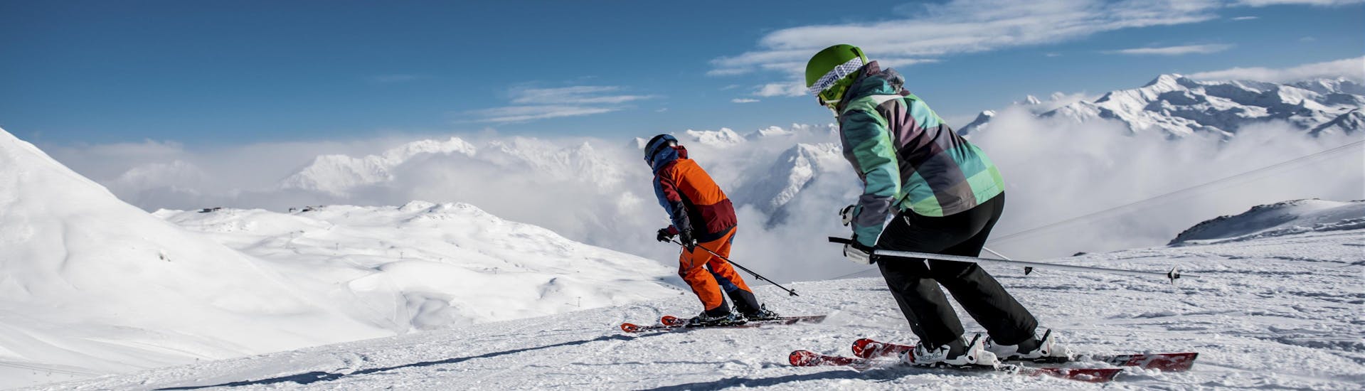 Zwei Skifahrer beim Skifahren auf einer frisch präparierten Piste in Klosters, einem beliebten schweizer Skigebiet in dem viele bei einer der örtlichen Skischulen einen Skikurs buchen.