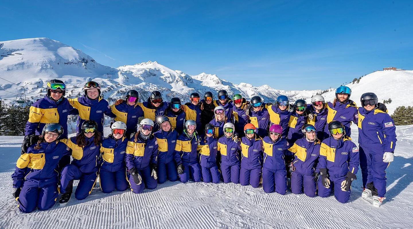 Une photo d&#x27;équipe des moniteurs de Skischule Koch souriant à l&#x27;appareil photo, les montagnes enneigées de la station de ski d&#x27;Obertauern en arrière-plan.