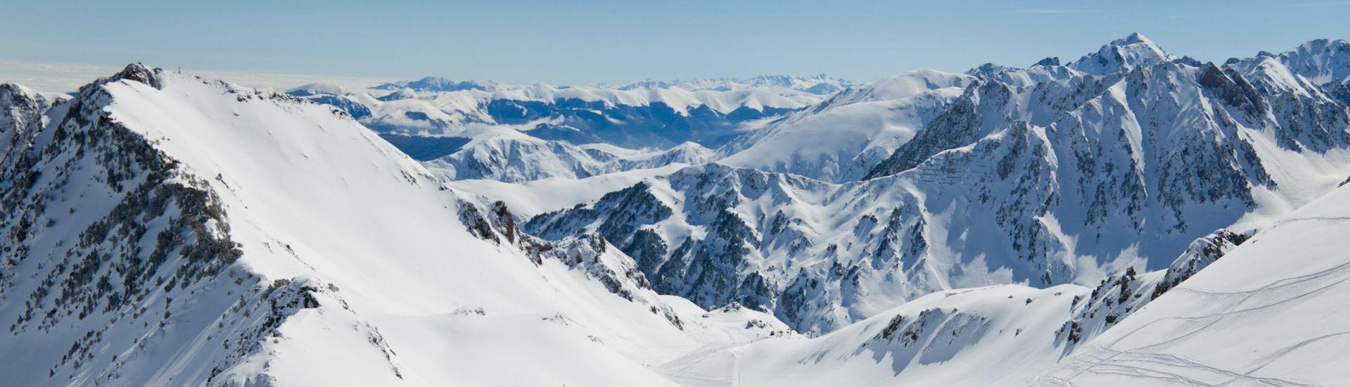 A snowboarder is admiring the stunning view of the snow-capped Pyrenees from one of the ski slopes in La Mongie - Tourmalet, where local ski schools offer a range of different ski lessons.