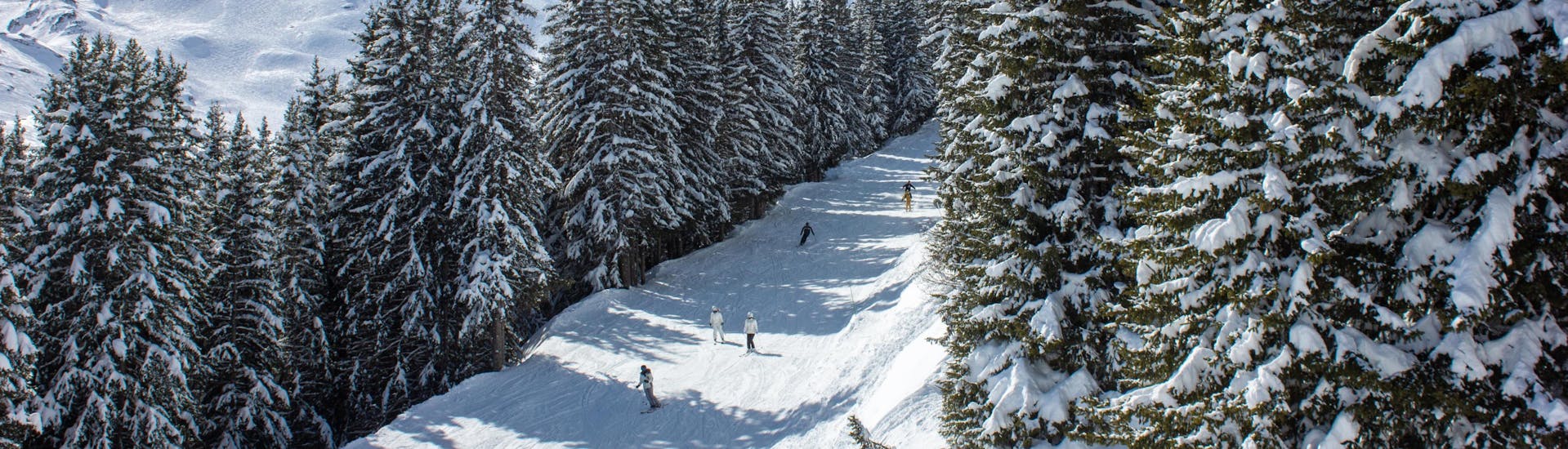 A group of skiers descend snow-covered mountain in La Tania in Courchevel during the winter season.