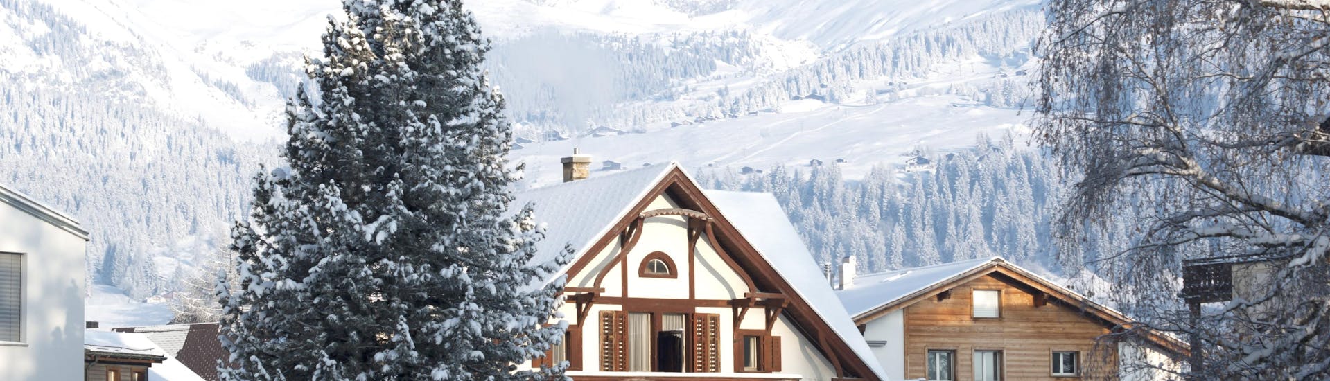 Une vue sur les chalets couverts de neige dans la station de ski suisse de Laax-Flims-Falera, où les visiteurs peuvent réserver des cours de ski avec l'une des écoles de ski locales.