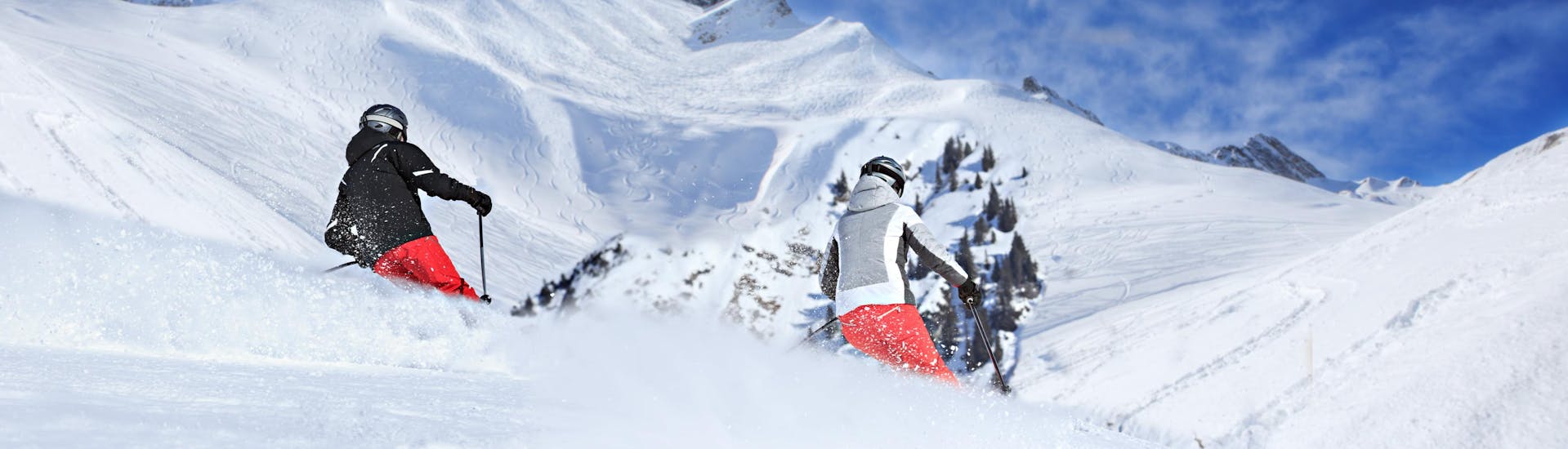 Zwei Skifahrer fahren bei ihrem Skikurs in Lech Zürs durch frischen Pulverschnee.