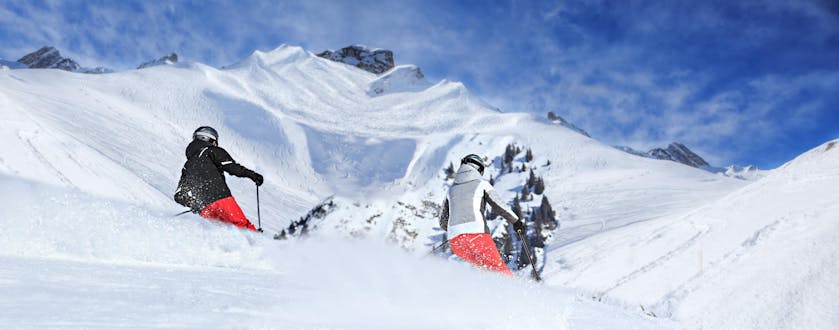 Zwei Skifahrer fahren bei ihrem Skikurs in Lech durch frischen Pulverschnee.
