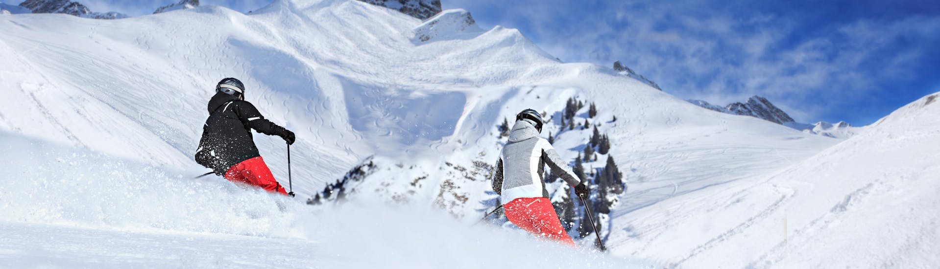 Zwei Skifahrer fahren bei ihrem Skikurs in Lech durch frischen Pulverschnee.