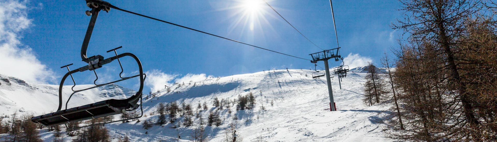 Un télésiège rejoint le sommet d'une montagne aux Orres, tandis qu'un groupe de skieurs participant à une série de cours de ski organisés par l'une des écoles de ski locales dévale la pente en contrebas.