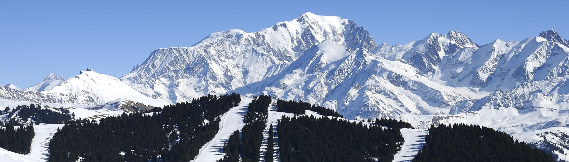 A picturesque view of ski slopes of Les Saisies, a French ski resort nestled between the majestic peaks of the Savoy department, where local ski schools offer a broad range of ski lessons for anyone who wishes to learn to ski.