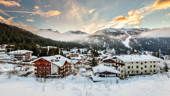 An image of the sun setting behind the mountains in the italian ski resort of Madonna di Campiglio, where visitors can learn to ski during their ski lessons provided by local ski schools.