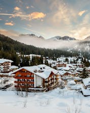 An image of the sun setting behind the mountains in the italian ski resort of Madonna di Campiglio, where visitors can learn to ski during their ski lessons provided by local ski schools.