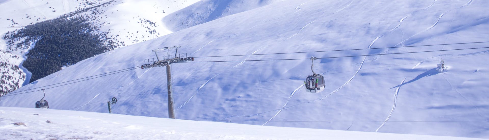 An image of a gondola carrying skiers up to the top of the mountain in the Catalonian ski resort of Masella, where visitors can book ski lessons with one of the local ski schools.