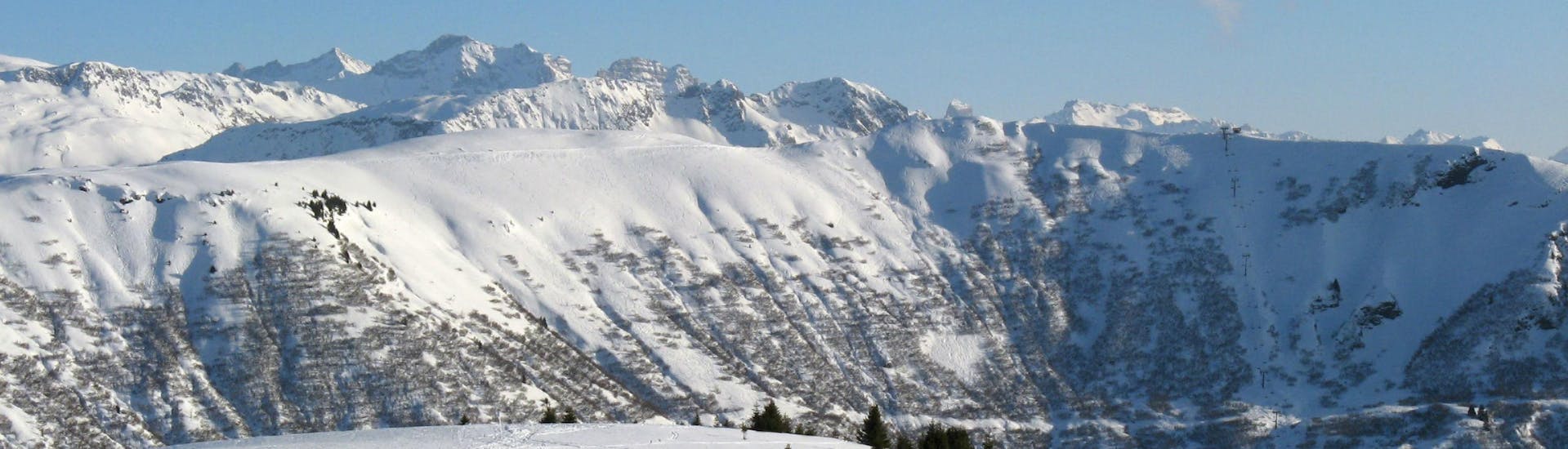 Une vue panoramique des pistes de ski de Notre Dame de Bellecombe, une station de ski française nichée entre les majestueux sommets du département de la Savoie, où les écoles de ski locales offrent un large choix de cours de ski.