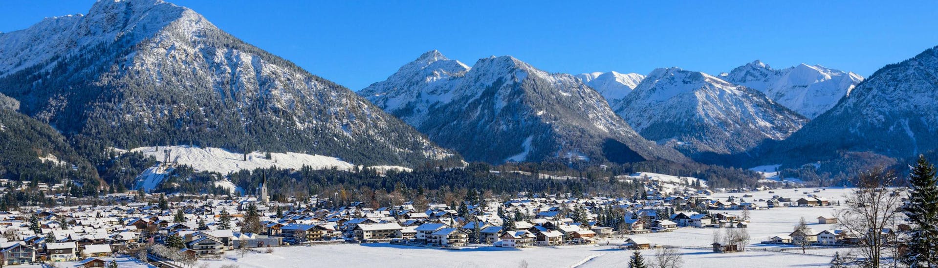 Een blik op het gezellige dorp Oberstdorf en de omringende bergen waar jong en oud van skilessen kan genieten.