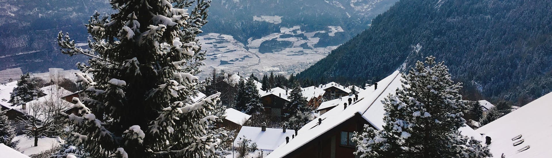 Une vue sur les toits enneigés du village suisse d'Ovronnaz, une station de ski populaire où les visiteurs peuvent réserver un cours de ski dans l'une des écoles de ski locales.