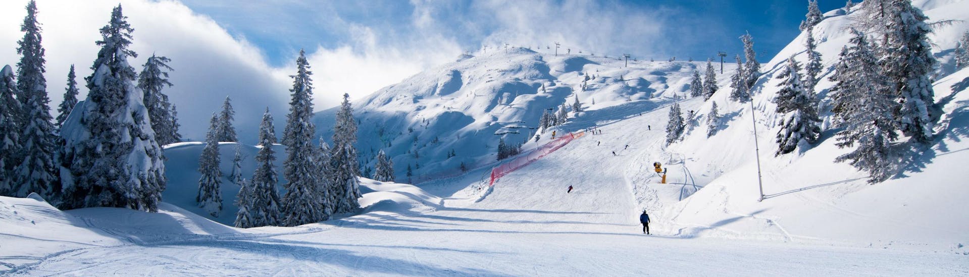 Una coppia di sciatori scia lungo una pista da sci appena battuta nella stazione sciistica italiana di Paganella Ski, dove le scuole di sci locali offrono numerose lezioni di sci.