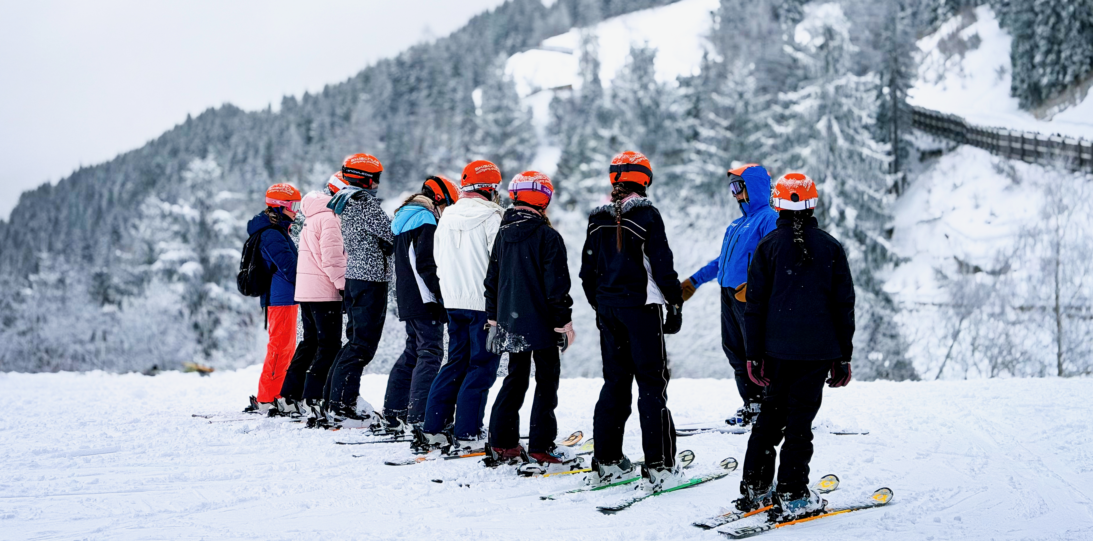Group of skiers during a ski lesson with Ski School Wolfgang Pfeifhofer in Alpendorf – St. Johann im Pongau, with panoramic views of the snow-covered Alps above a sea of clouds.