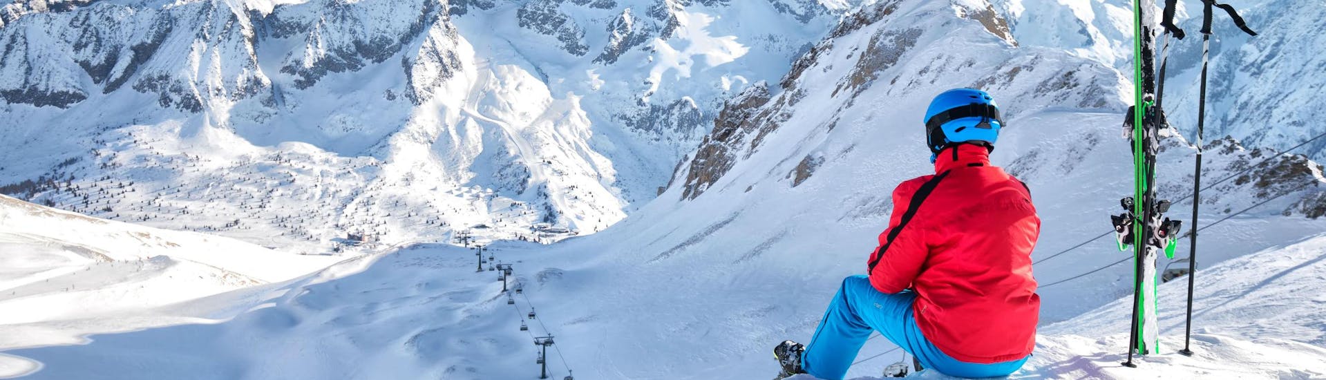 Uno sciatore sta facendo una pausa durante una delle lezioni di sci nel comprensorio sciistico di Ponte di Legno ammirando il panorama innevato mozzafiato.