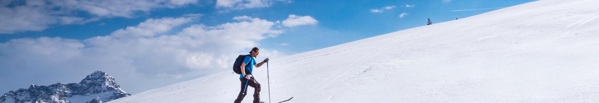 Ein Skitourengeher steigt an einem sonnigen Tag die Piste in Riezlern, Österreich, hinauf.