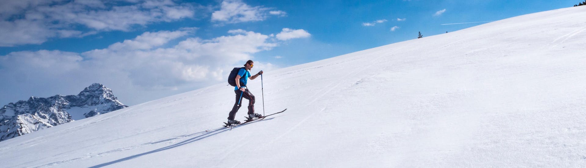 Ein Skitourengeher steigt an einem sonnigen Tag die Piste in Riezlern, Österreich, hinauf.
