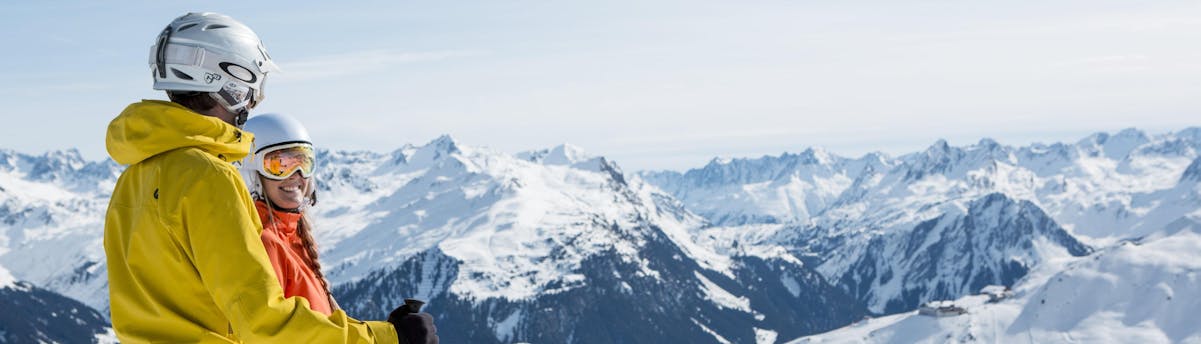 ski-school-schruns_SEM-Resort-Hero_(c)Montafon Tourismus GmbH Schruns_Silvretta Montafon A man and a woman are looking out over the beautiful panorama of the Montafon mountain range, as they partake in their ski lessons with one of the local ski schools in Schruns.